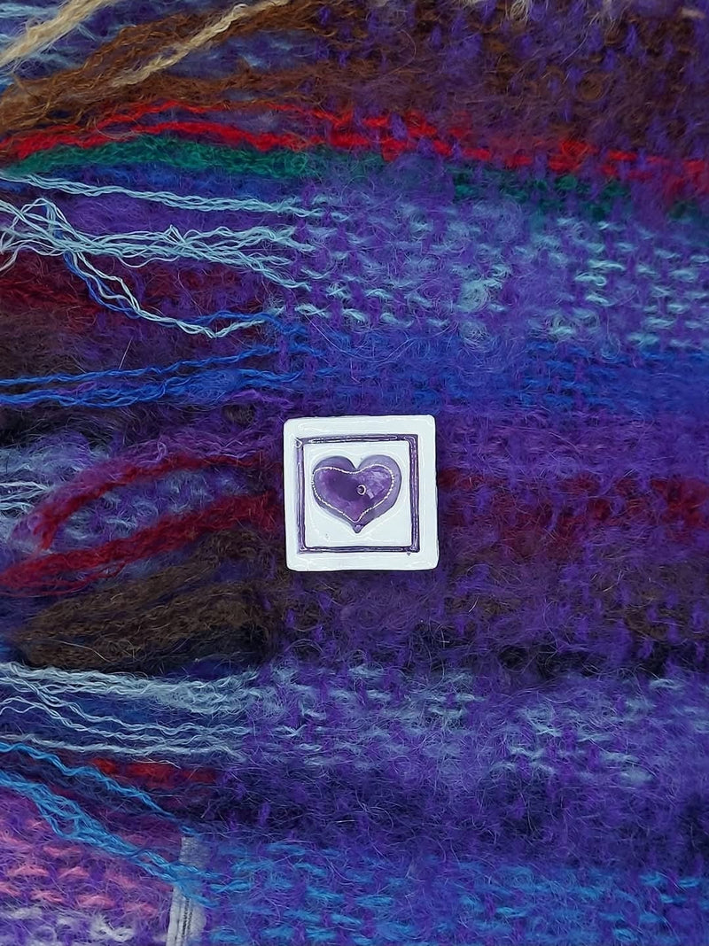 Heart-shaped ceramic brooch on tweed fabric